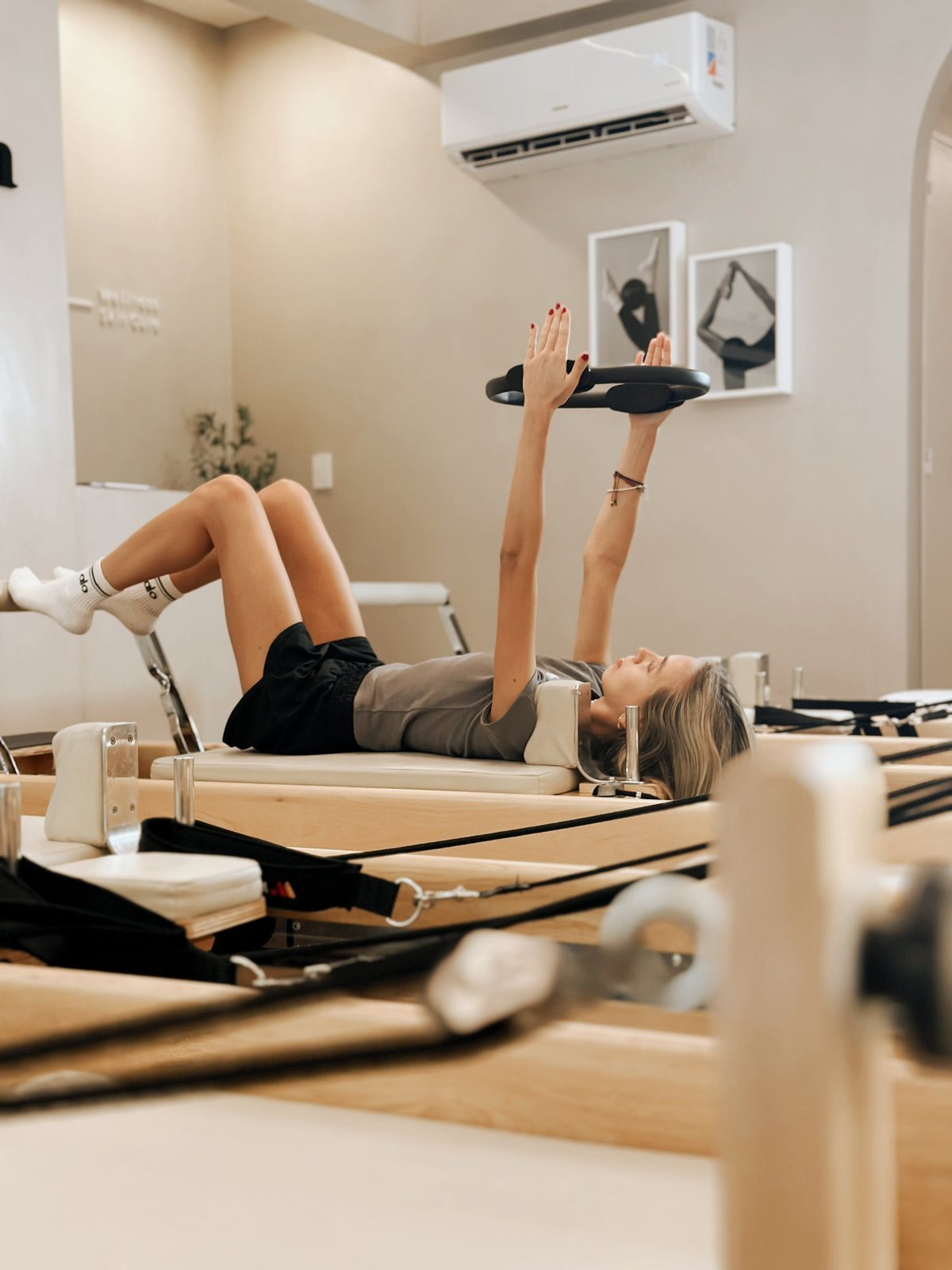 Alumna acostada en el reformer con aro de pilates